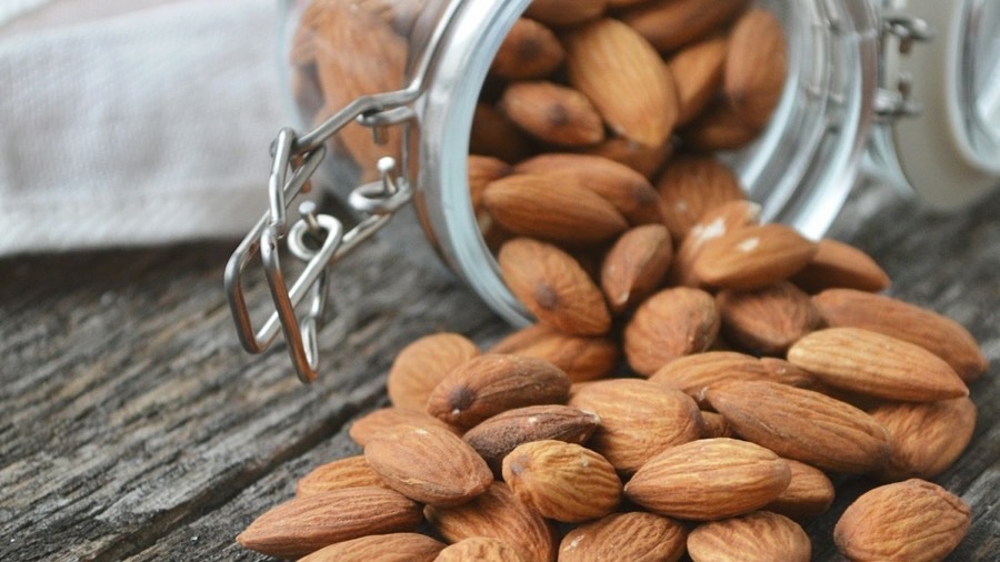 Almonds spilling from a glass jar, a food source of biotin