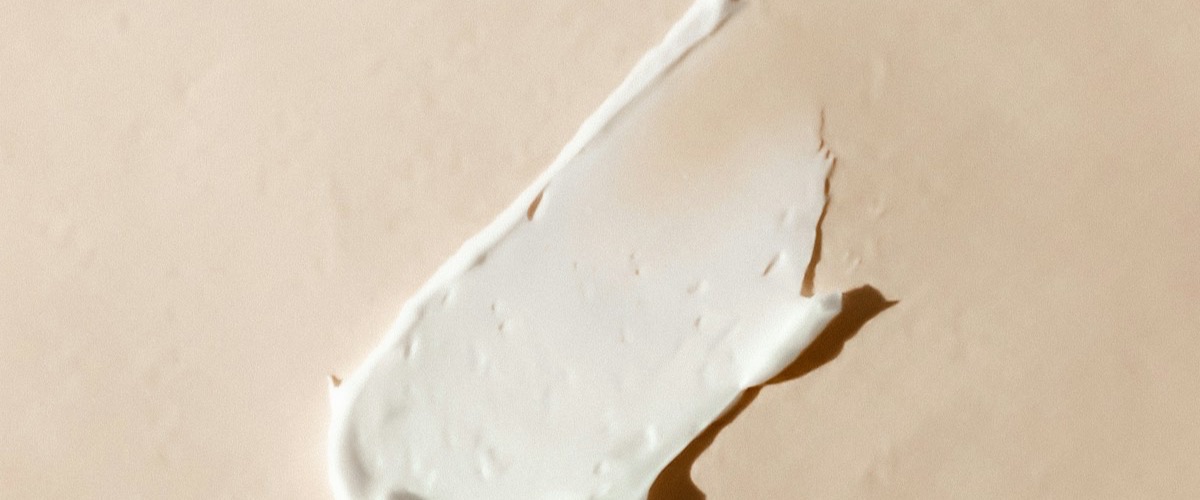 Face cream spread over a beige surface